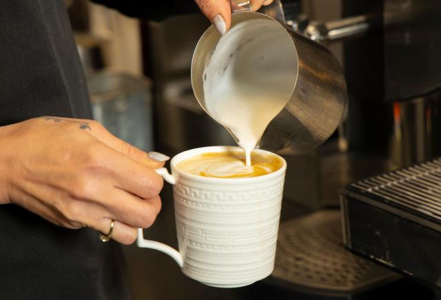 Barista pouring milk into coffee in House of Waterford Café